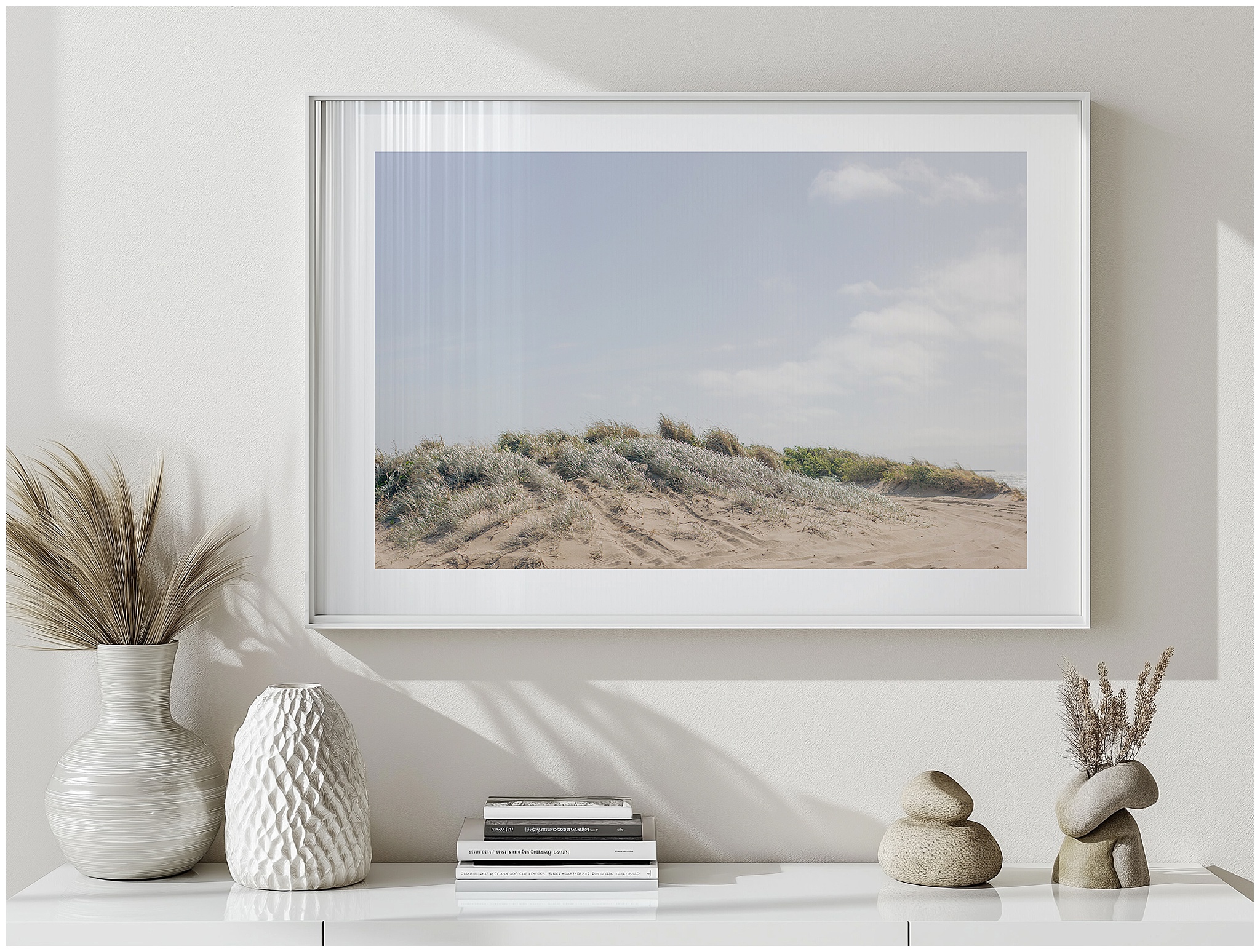 Minimal sideboard styled with a large landscape artwork of serene sand dunes and soft coastal grasses in warm morning light.